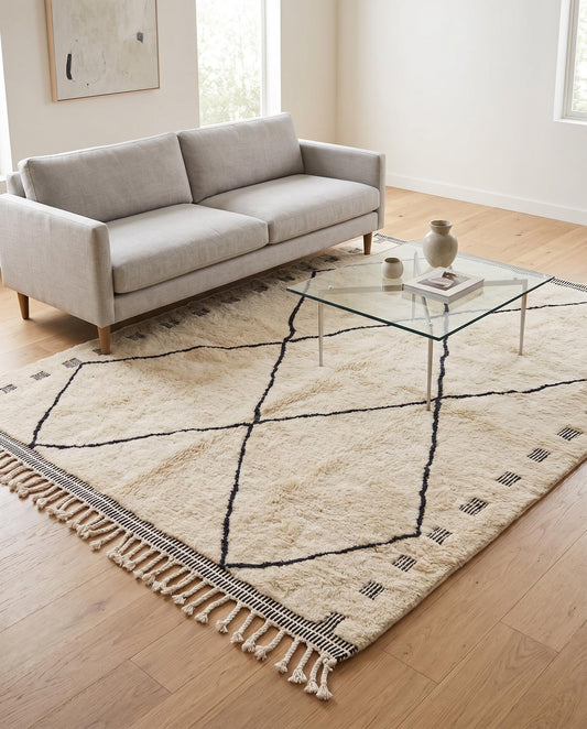 A minimalist cream and black diamond lattice Mrirt Moroccan rug styled in a bright contemporary living room by NURA.