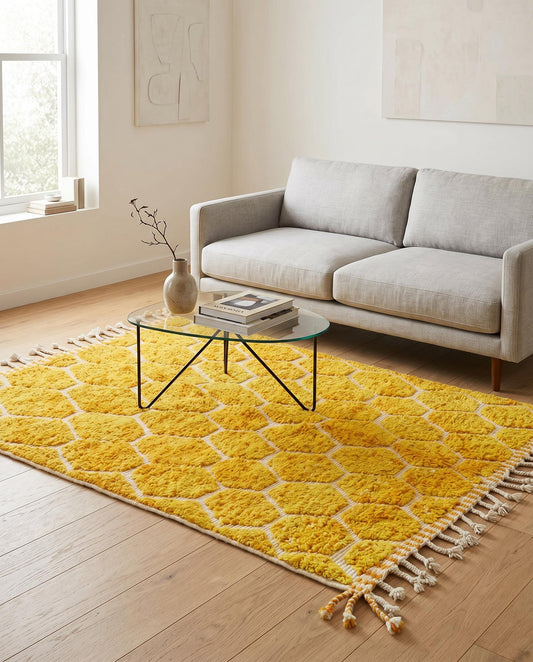A bright mustard yellow honeycomb Moroccan rug by NURA styled in a modern living room, adding warm texture to the floor.