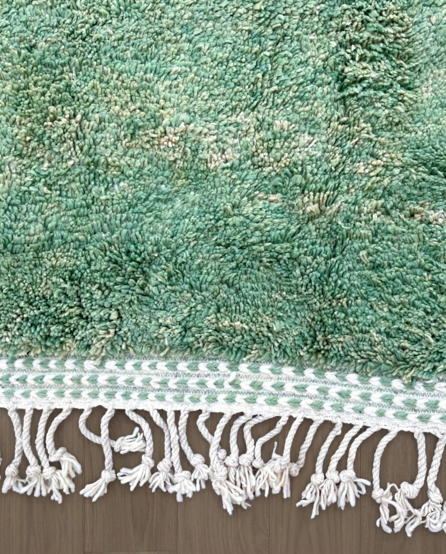 LATIFA Beni Ourain green asymmetrical diamond lattice Moroccan rug close-up of hand-tied fringe and kilim band detail, by NURA