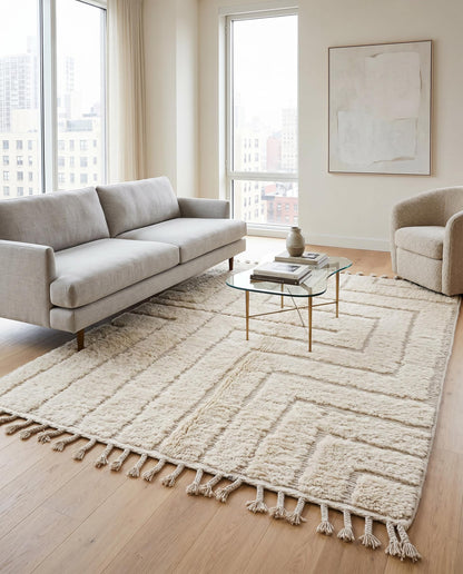 A textured cream Moroccan rug with a raised geometric maze pattern styles a modern living room with minimalist decor by NURA.