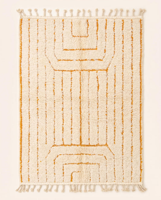 A plush cream Moroccan rug featuring minimalist saffron geometric lines and braided fringe, hand-knotted from wool by NURA.