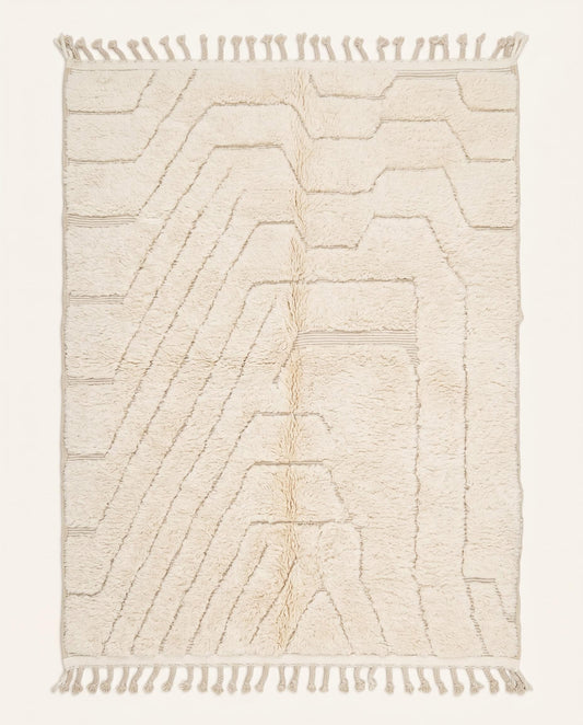 A minimalist Beni Ourain Moroccan rug by NURA featuring a plush cream wool pile with carved geometric lines and braided tassels.