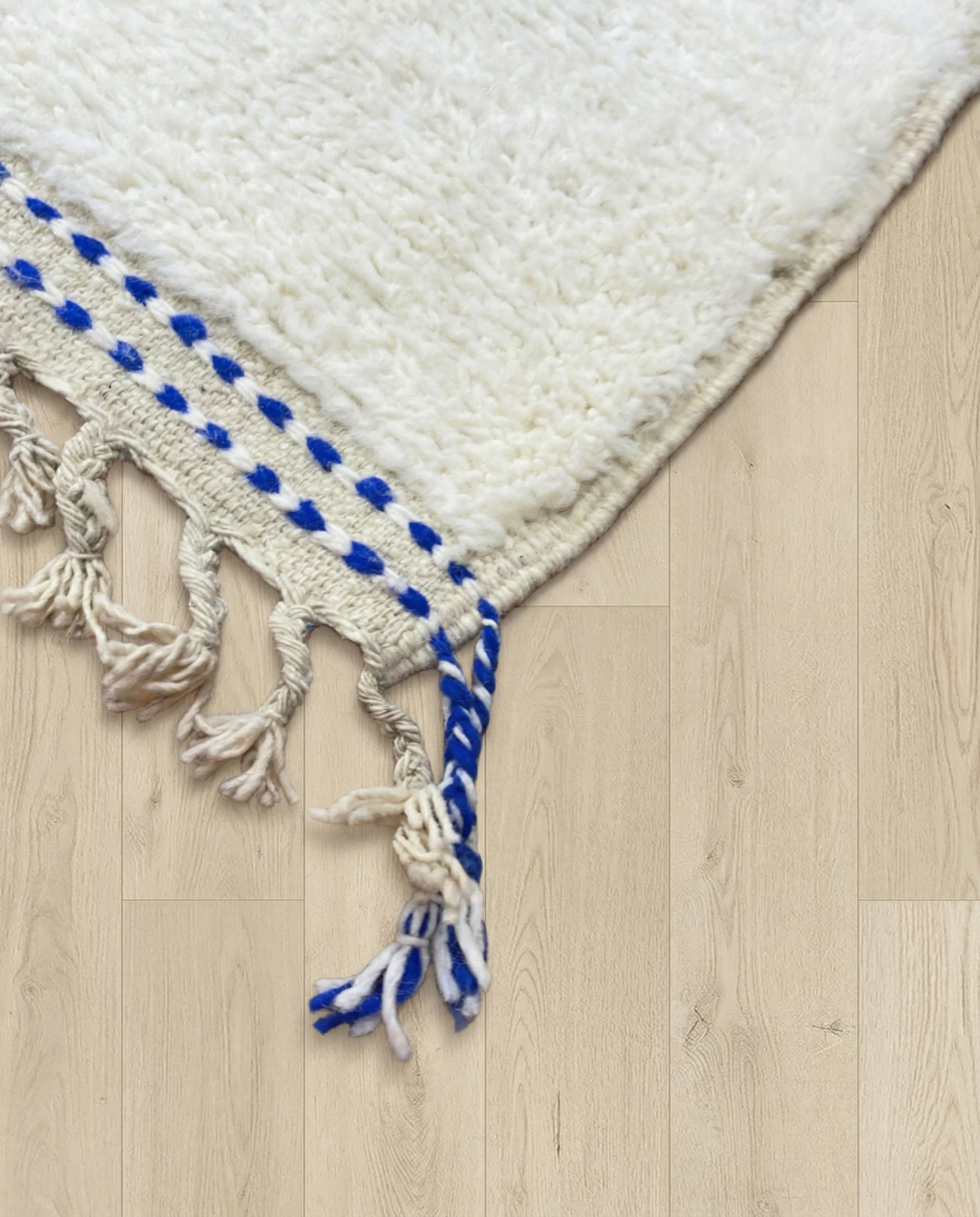 AMANI Beni Ourain ivory bold striped field Moroccan rug close-up of hand-tied fringe and kilim band detail, by NURA