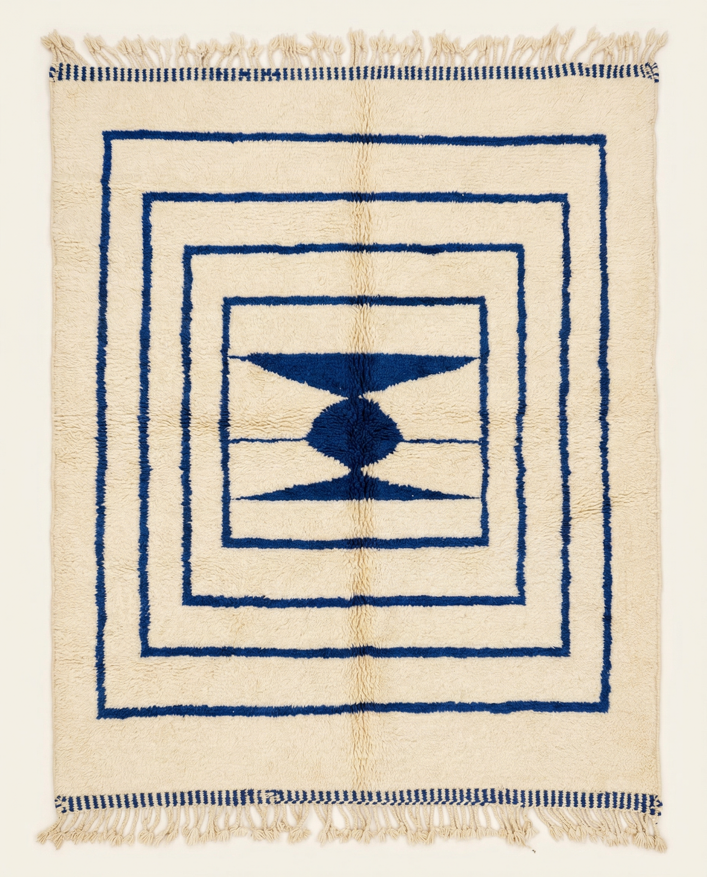 Plush cream Beni Ourain Moroccan rug with bold navy nested borders and a central geometric medallion, by NURA.