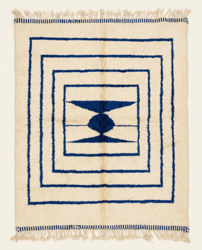 Plush cream Beni Ourain Moroccan rug with bold navy nested borders and a central geometric medallion, by NURA.