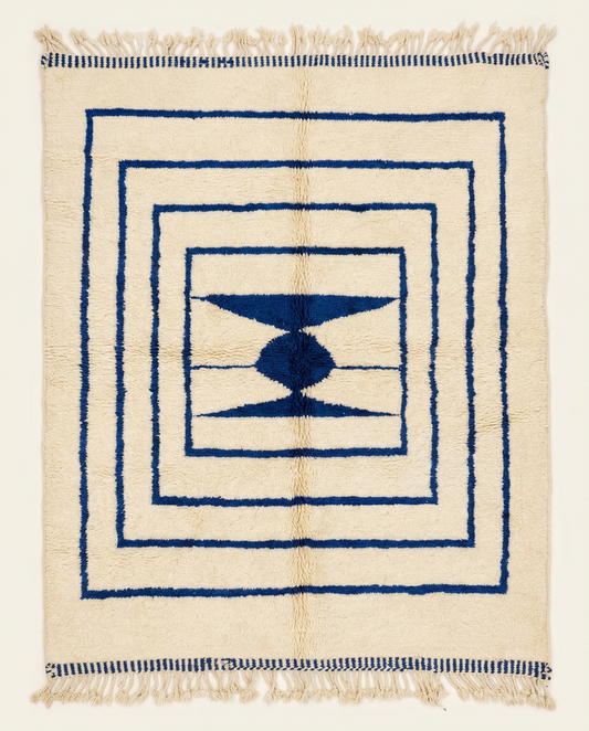 Plush cream Beni Ourain Moroccan rug with bold navy nested borders and a central geometric medallion, by NURA.