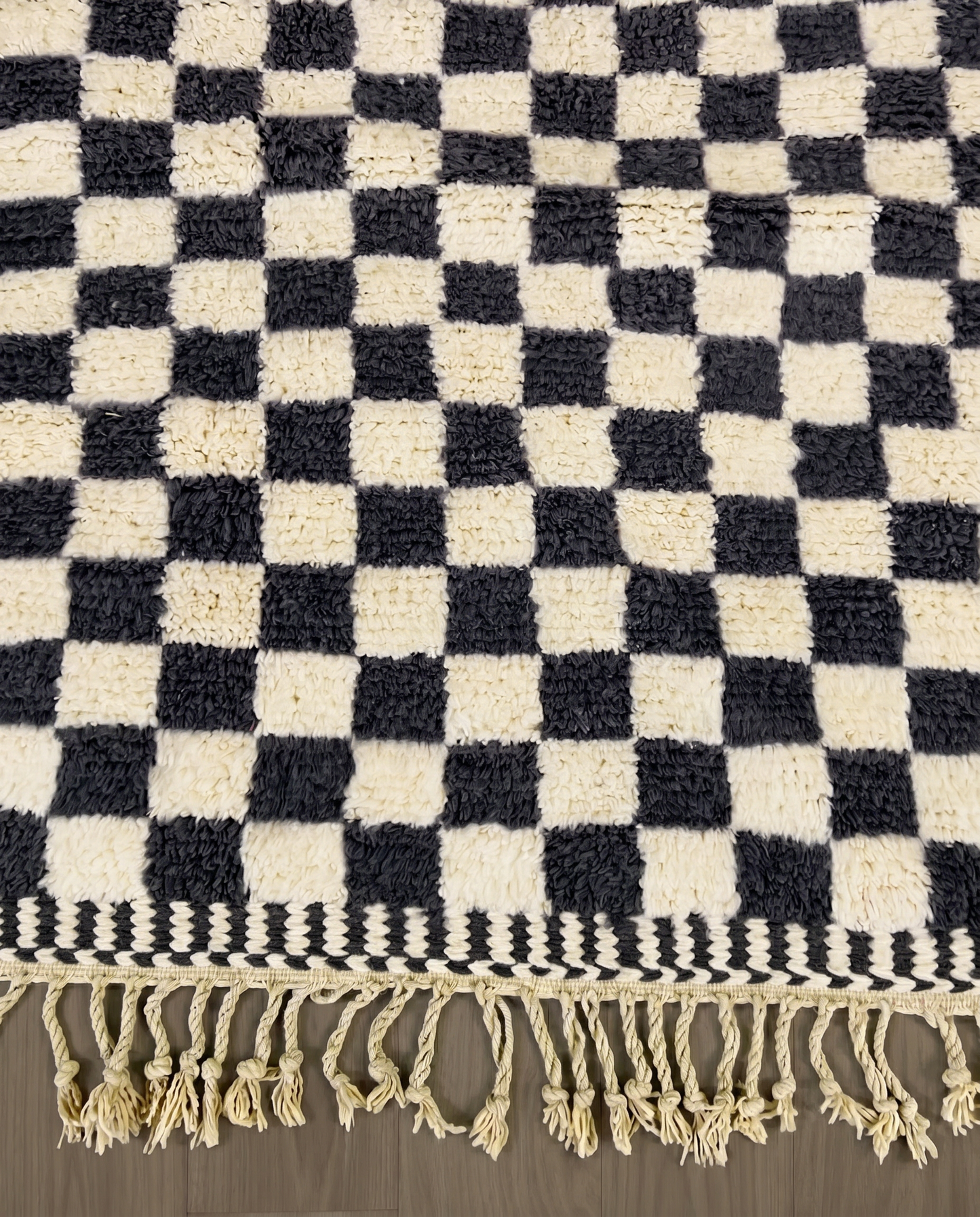 ANISSA Beni Ourain black checkerboard grid Moroccan rug close-up of hand-tied fringe and kilim band detail, by NURA