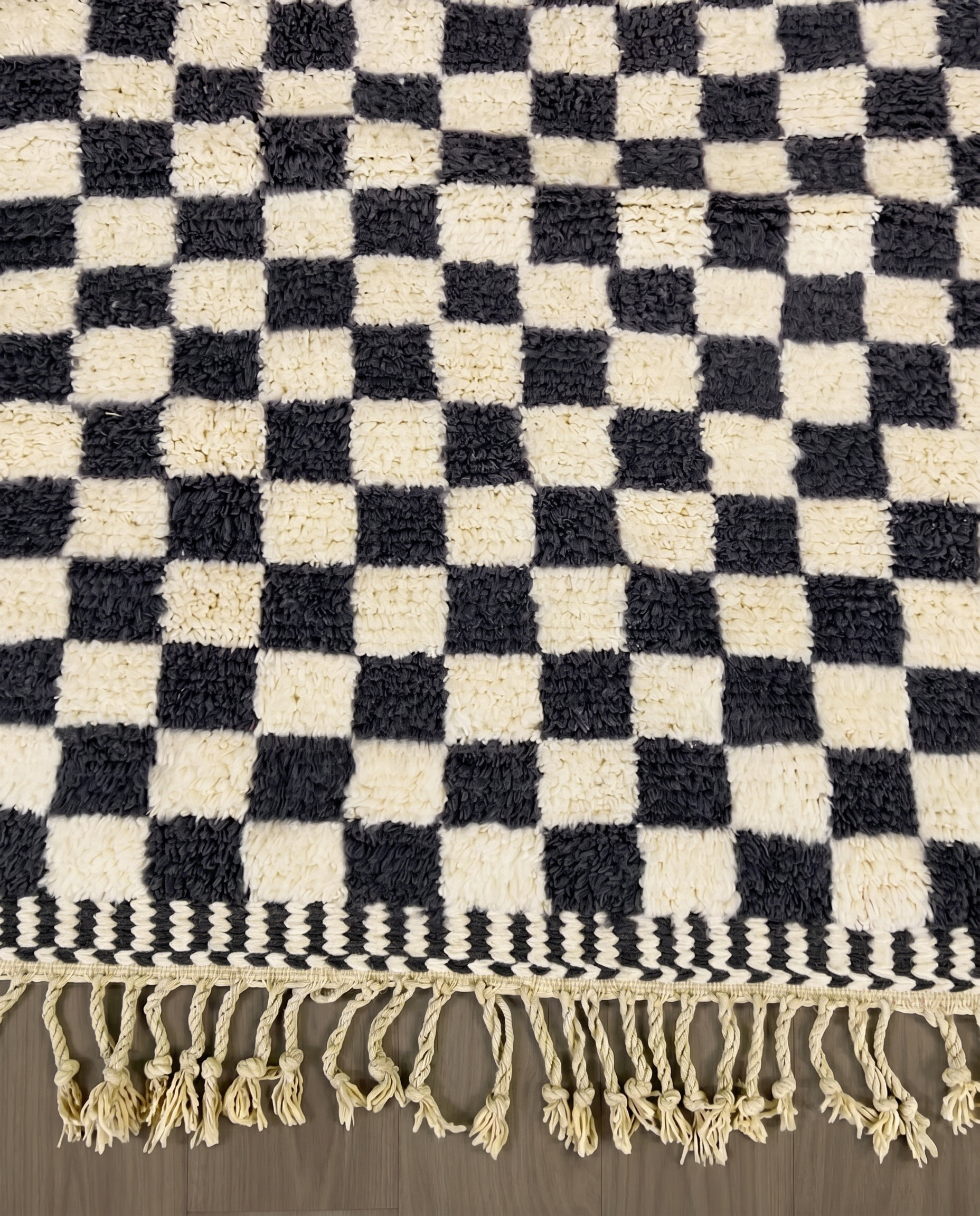 ANISSA Beni Ourain black checkerboard grid Moroccan rug close-up of hand-tied fringe and kilim band detail, by NURA