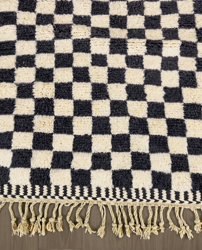 ANISSA Beni Ourain black checkerboard grid Moroccan rug close-up of hand-tied fringe and kilim band detail, by NURA