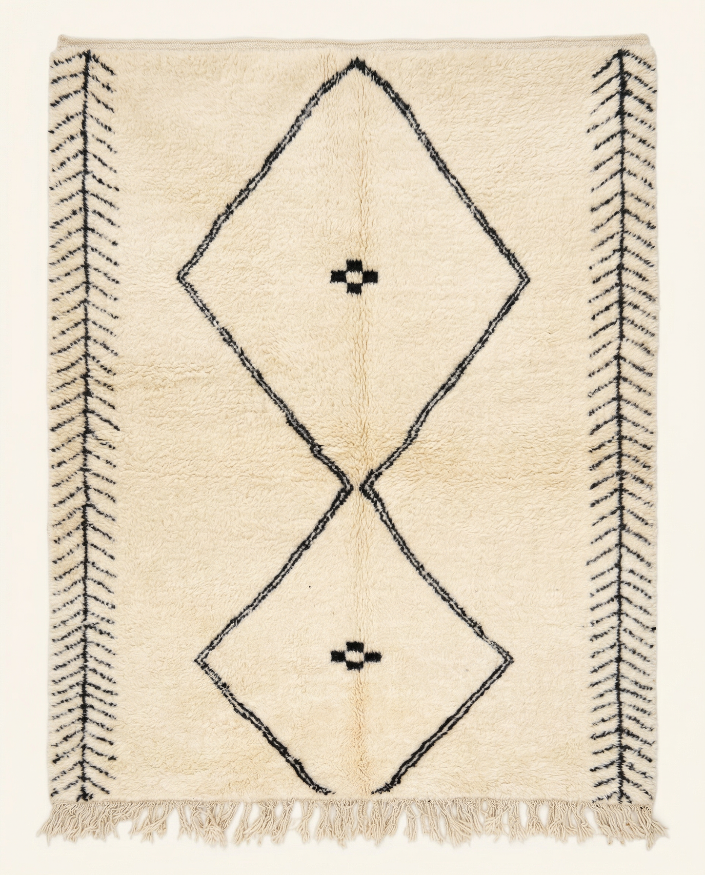 Plush cream Beni Ourain Moroccan rug with a large black double diamond motif and herringbone end bands, by NURA.