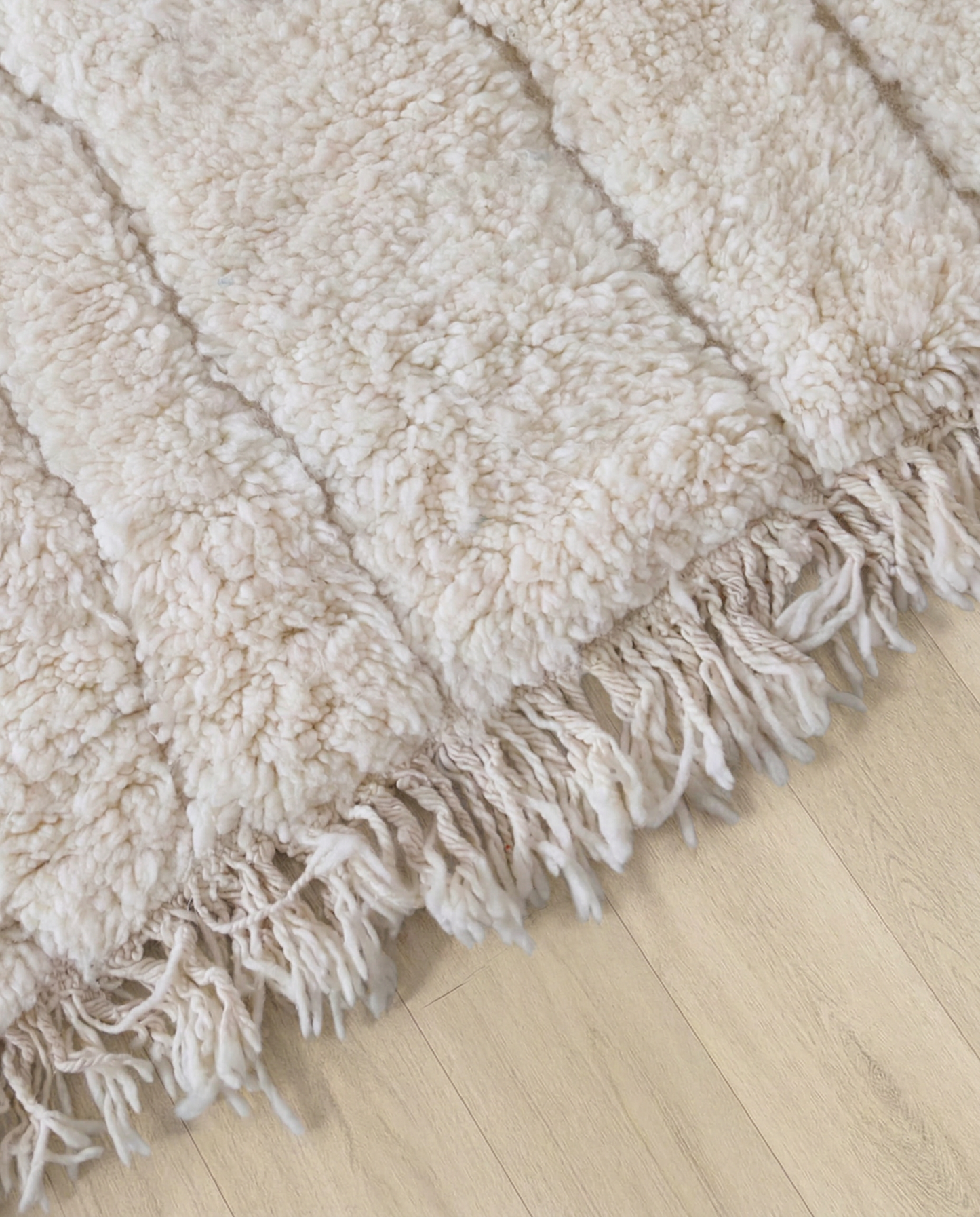 AYA Beni Ourain cream carved linear grid Moroccan rug close-up of hand-tied fringe and kilim band detail, by NURA