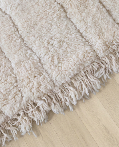 AYA Beni Ourain cream carved linear grid Moroccan rug close-up of hand-tied fringe and kilim band detail, by NURA