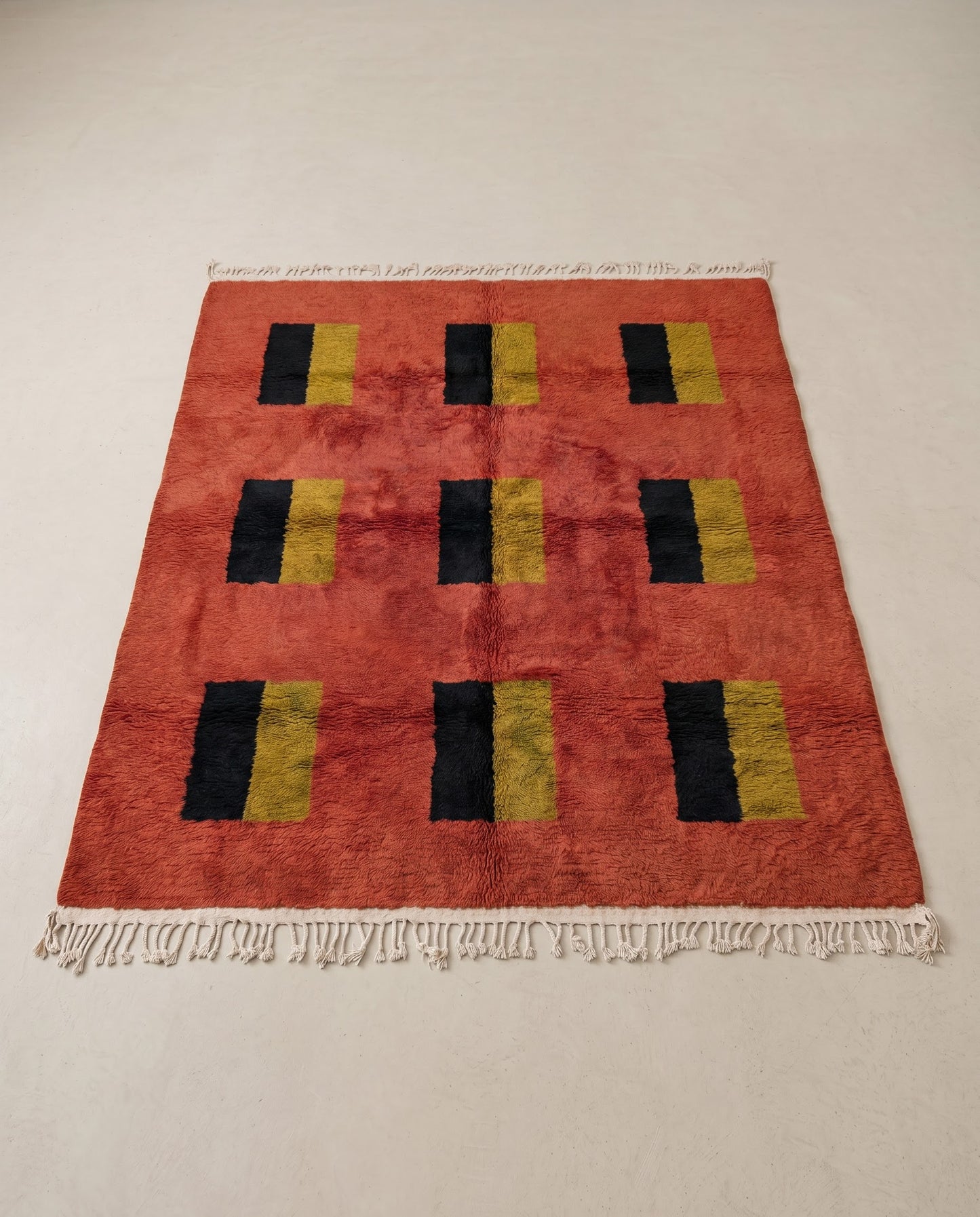 BILSAN Beni Ourain terracotta color block grid Moroccan rug displayed on a parquet wood floor, showing full fringe and edge detail, by NURA
