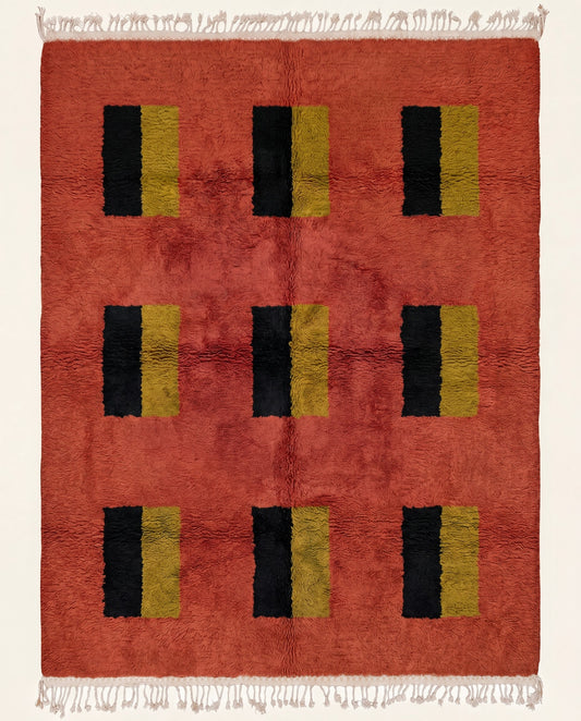 A plush Moroccan wool rug featuring a rich terracotta field with a modern grid of black and mustard yellow color blocks by NURA.