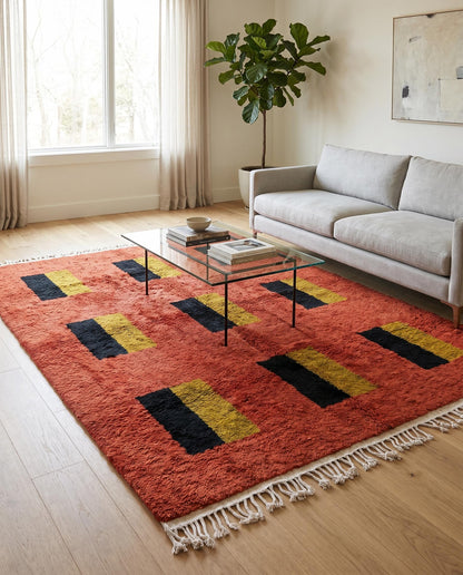 A vibrant terracotta Moroccan rug with a black and mustard color block grid styled in a modern living room setting by NURA.