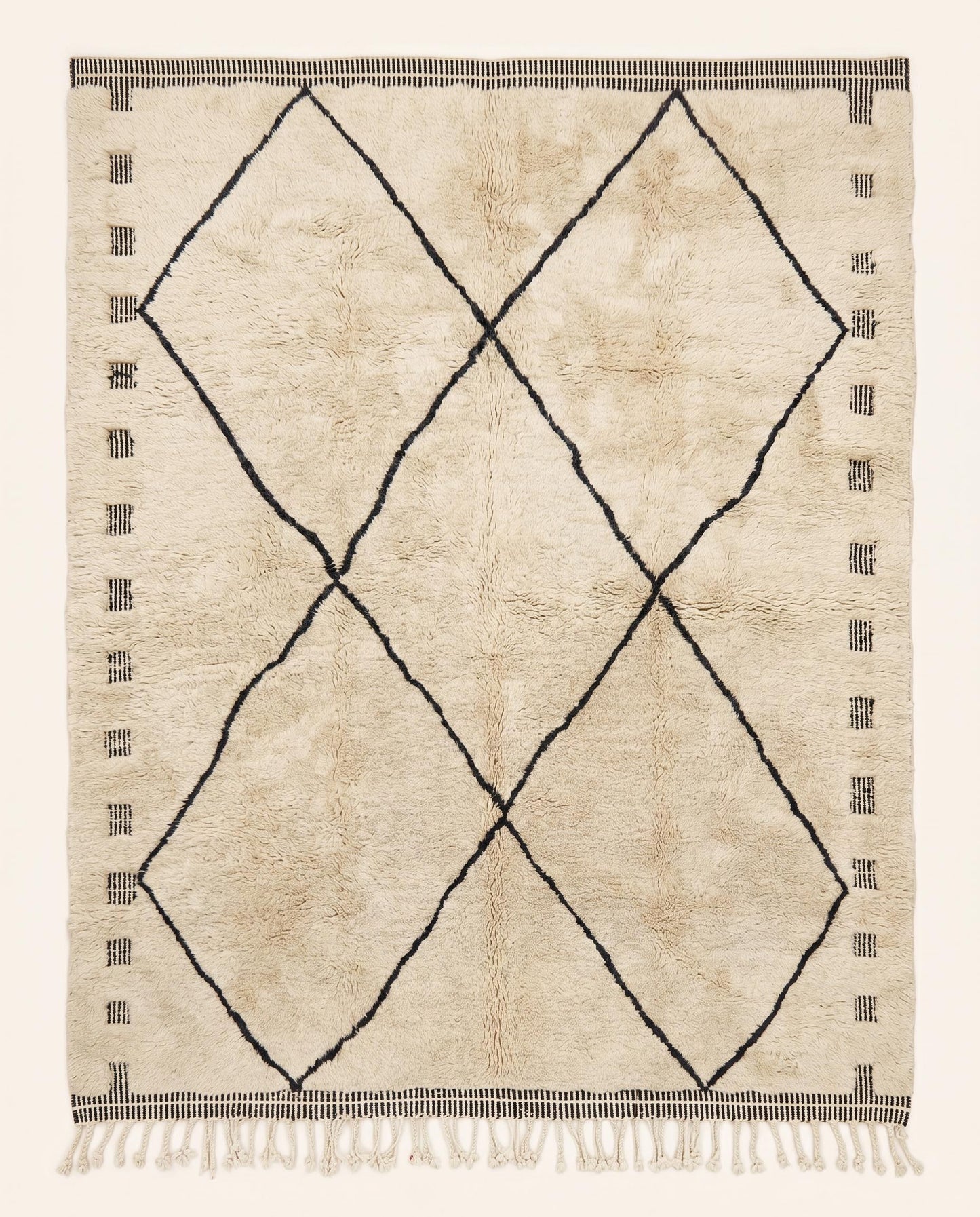 A plush cream Mrirt Moroccan rug featuring a minimalist black diamond lattice pattern, hand-knotted in wool by NURA.