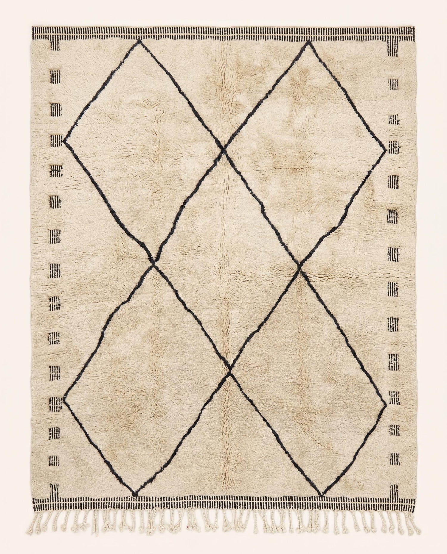 A plush cream Mrirt Moroccan rug featuring a minimalist black diamond lattice pattern, hand-knotted in wool by NURA.