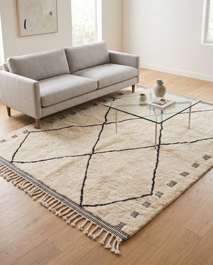 A minimalist cream and black diamond lattice Mrirt Moroccan rug styled in a bright contemporary living room by NURA.