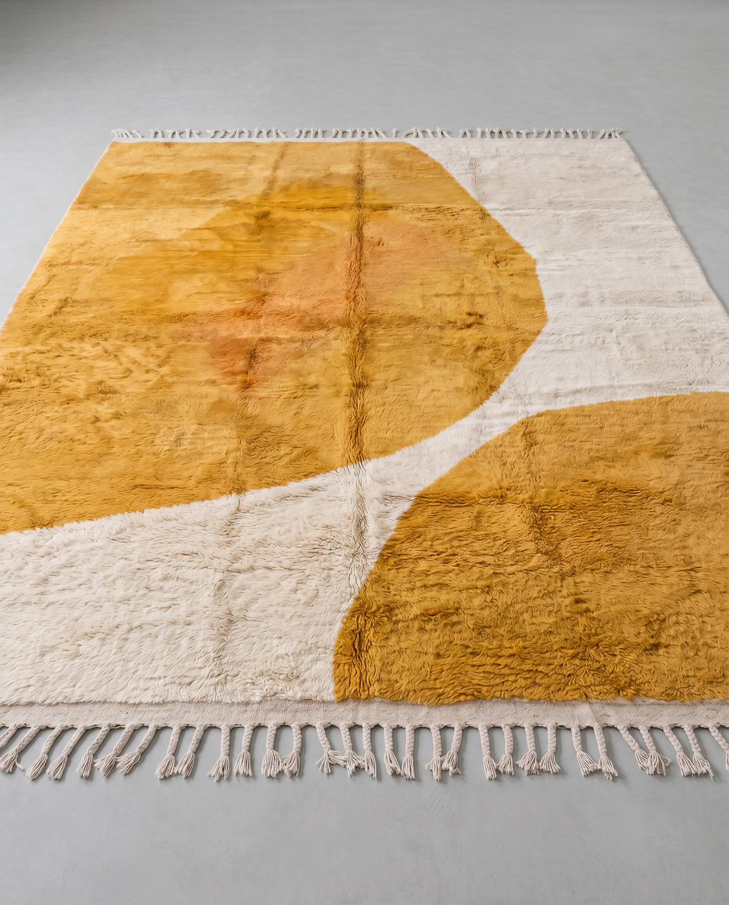 BISAN Beni Ourain mustard organic abstract Moroccan rug displayed on a parquet wood floor, showing full fringe and edge detail, by NURA