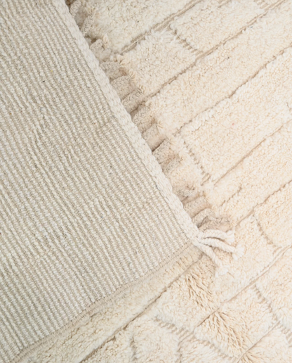BOUTHAINA Beni Ourain cream organic abstract Moroccan rug close-up of hand-tied fringe and kilim band detail, by NURA