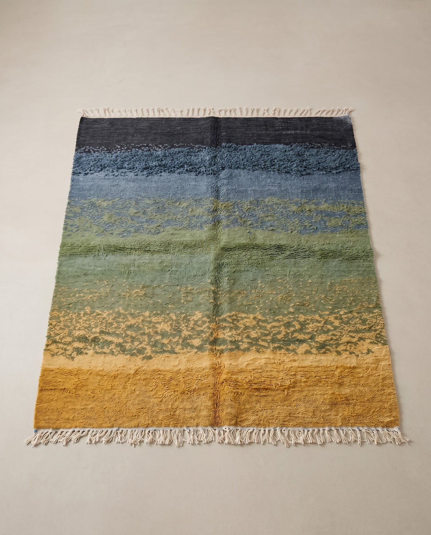 CHAIMA Azilal mustard abstract landscape Moroccan rug displayed on a parquet wood floor, showing full fringe and edge detail, by NURA