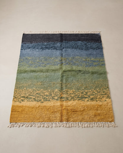 CHAIMA Azilal mustard abstract landscape Moroccan rug displayed on a parquet wood floor, showing full fringe and edge detail, by NURA