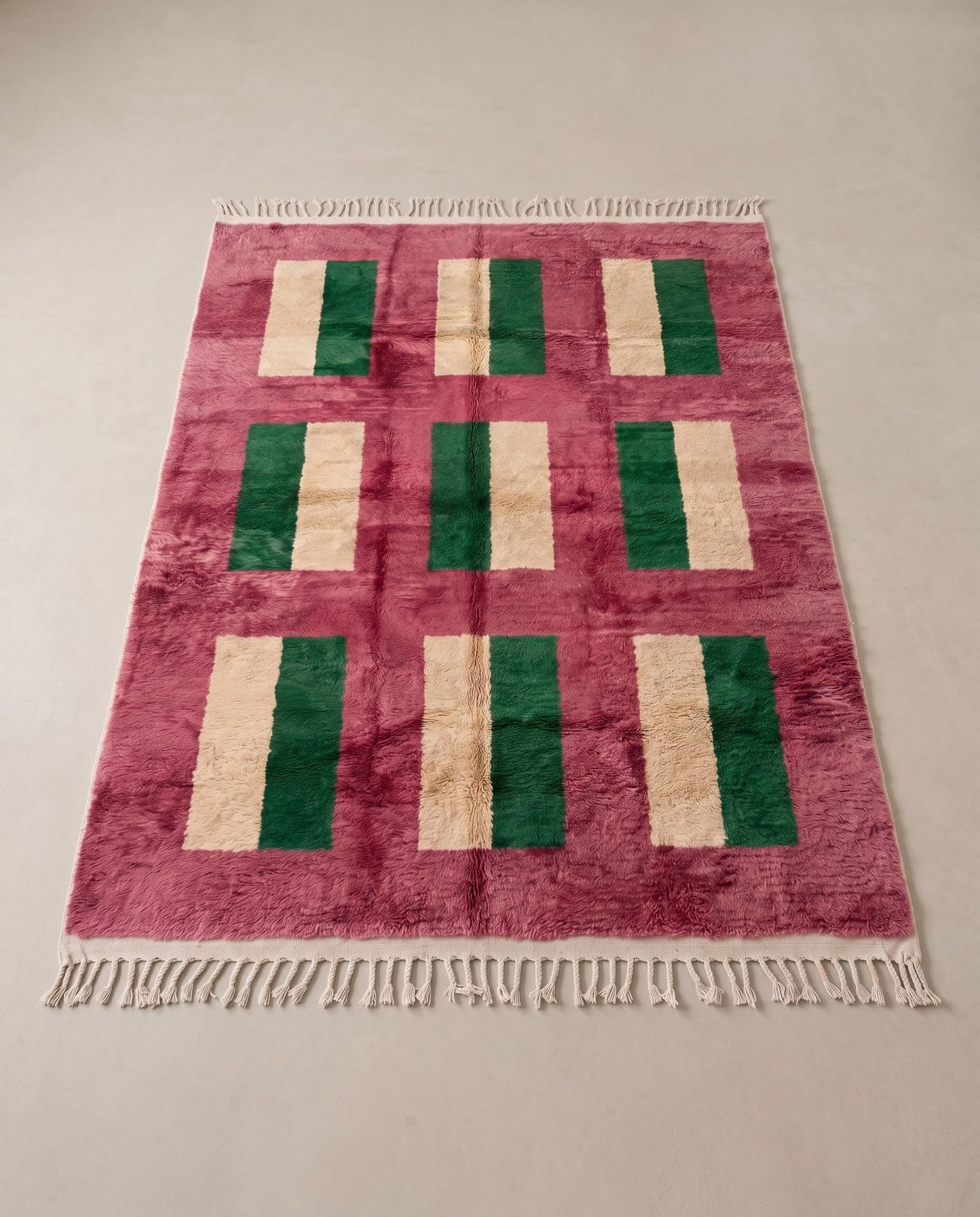 CHAMA Boujad rose color block Moroccan rug displayed on a parquet wood floor, showing full fringe and edge detail, by NURA
