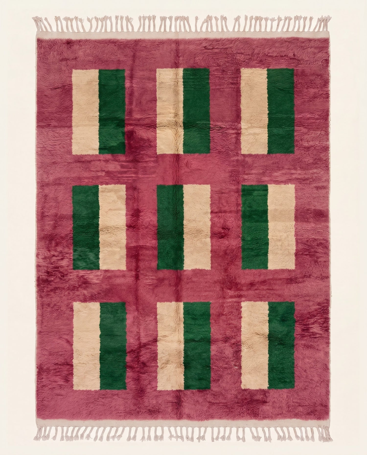 A plush contemporary Moroccan wool rug featuring a bold color block grid in dark green and cream on a vibrant rose field by NURA.