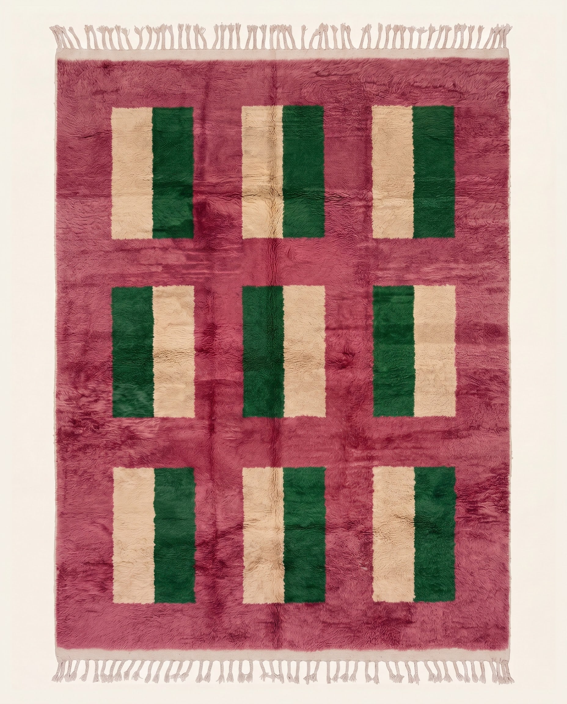 A plush contemporary Moroccan wool rug featuring a bold color block grid in dark green and cream on a vibrant rose field by NURA.