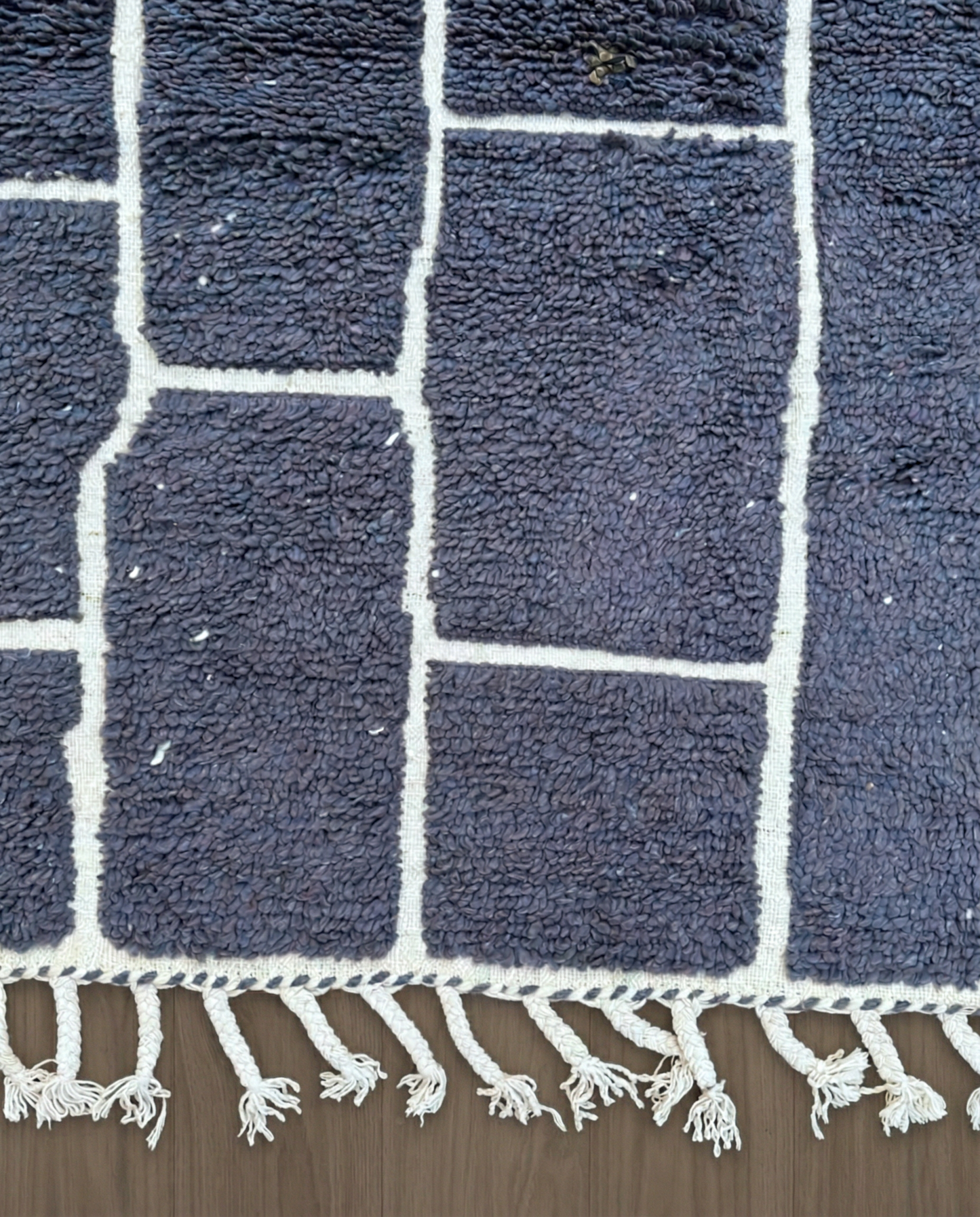 DANIA Beni Ourain charcoal irregular block grid Moroccan rug close-up of hand-tied fringe and kilim band detail, by NURA