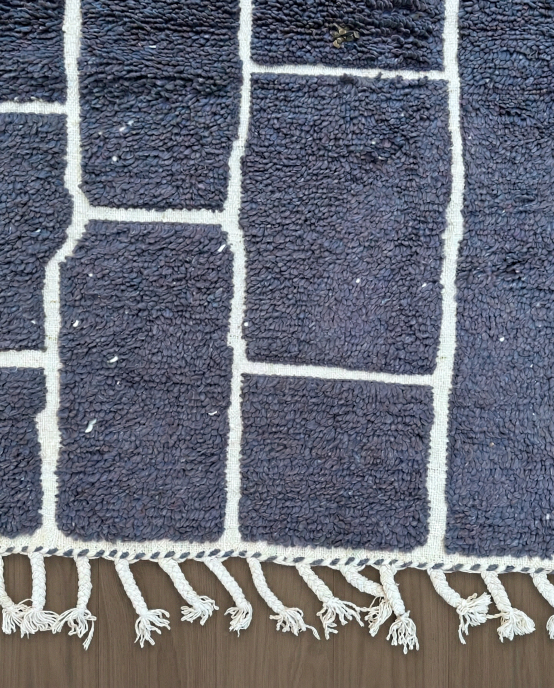 DANIA Beni Ourain charcoal irregular block grid Moroccan rug close-up of hand-tied fringe and kilim band detail, by NURA