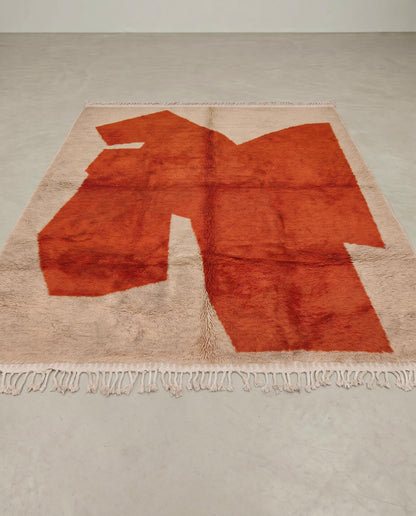 DIMA Beni Ourain rust abstract color block Moroccan rug displayed on a parquet wood floor, showing full fringe and edge detail, by NURA