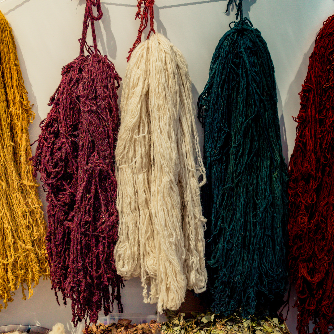 Natural Moroccan wool yarn hanging in rich colors, showing the dyed fibers used to handweave NURA wool rugs.