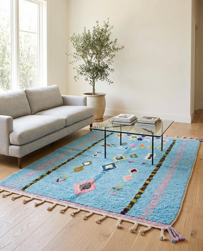 Vibrant sky blue Azilal Moroccan rug styled in a bright living room, adding a playful bohemian touch to the decor by NURA.