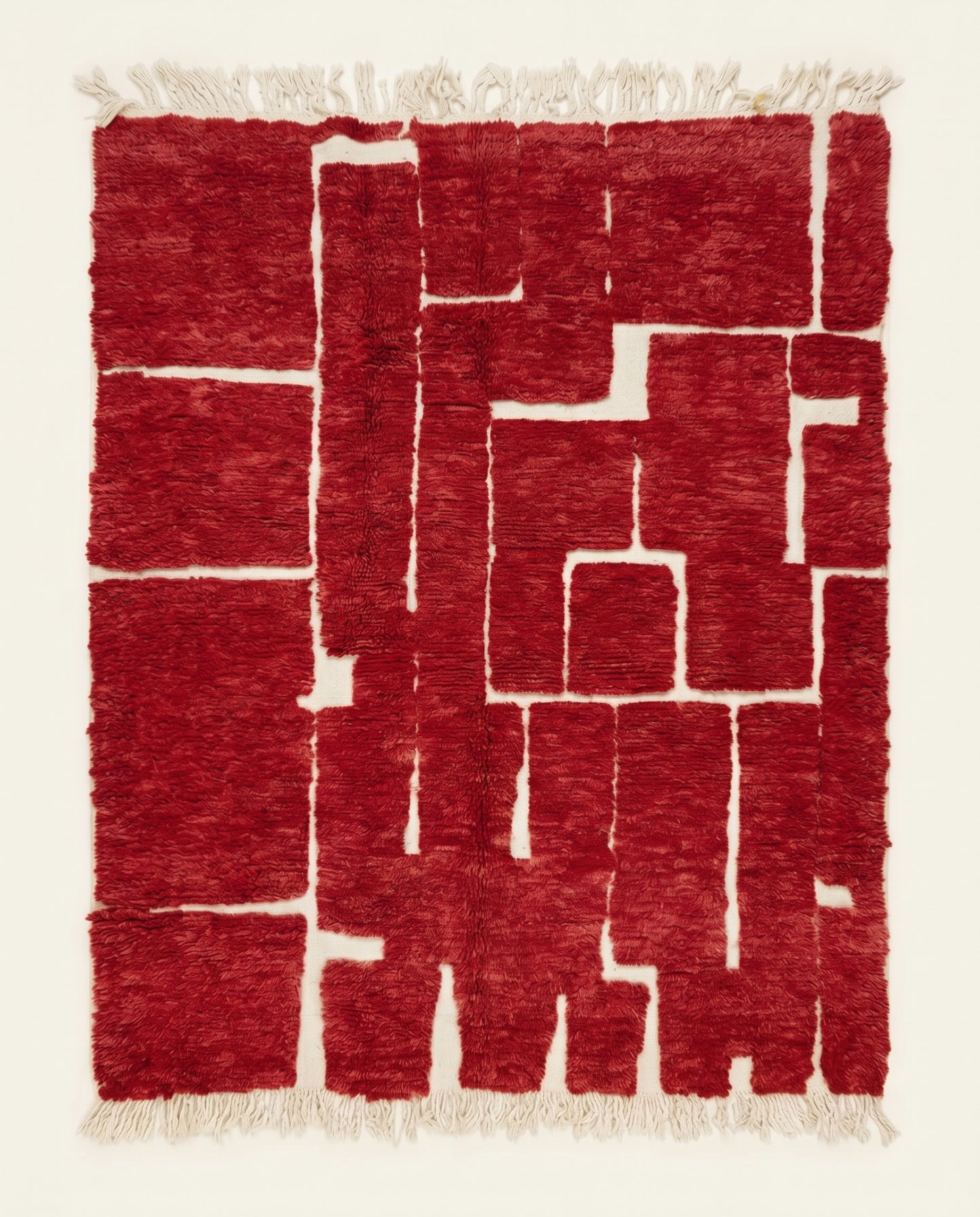A striking red Moroccan rug by NURA featuring an organic abstract pattern of plush crimson blocks and recessed cream lines.
