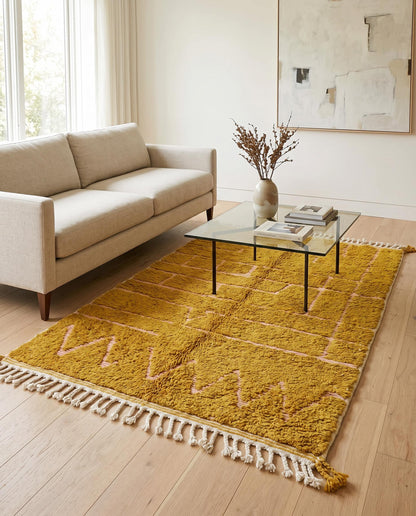 A plush mustard yellow Moroccan Azilal rug with pink geometric patterns styled in a bright, contemporary living room by NURA.