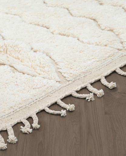 GHAZALA Beni Ourain cream diamond lattice Moroccan rug close-up of hand-tied fringe and kilim band detail, by NURA