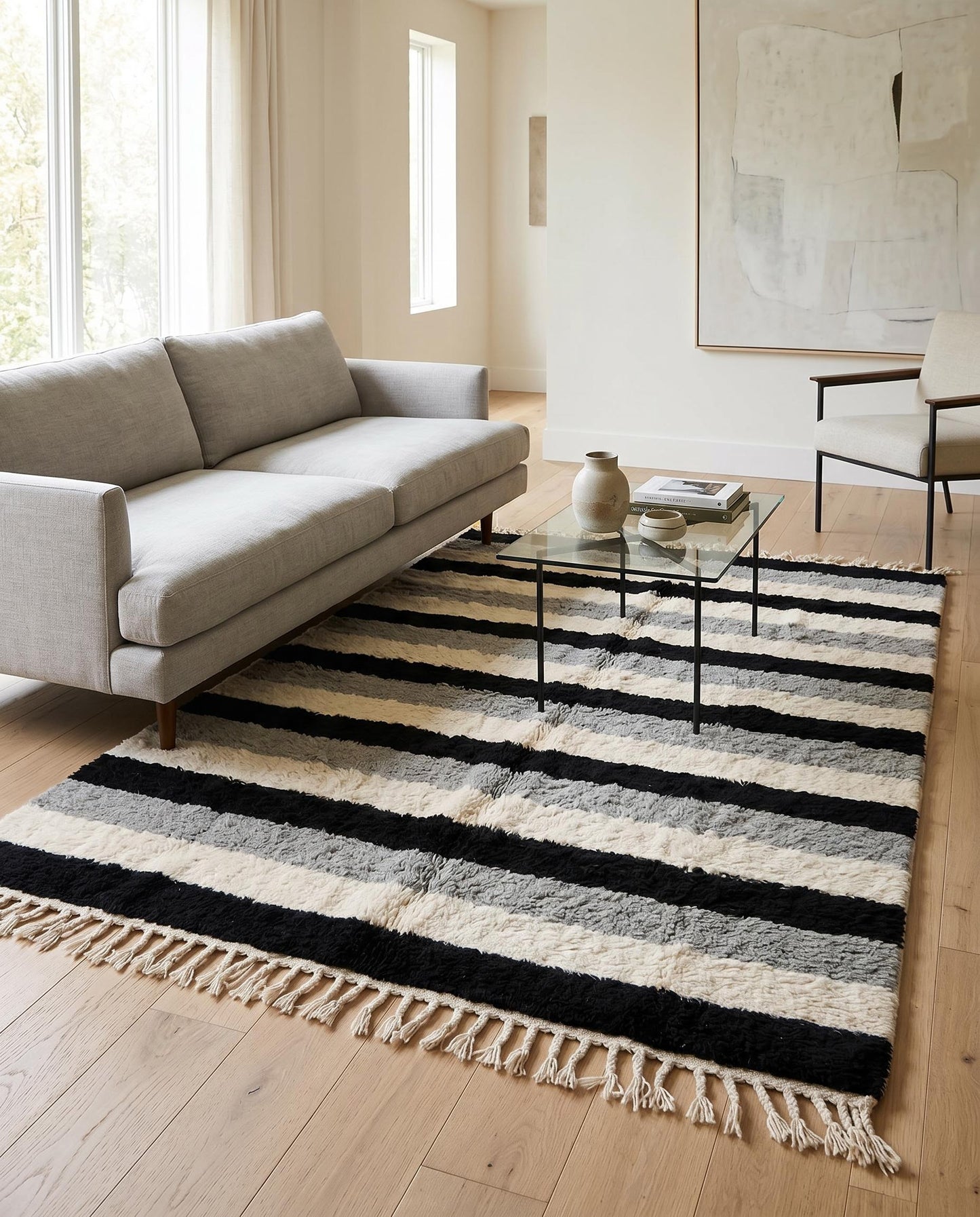 A striped Moroccan wool rug in black, cream, and grey styled in a modern living room with contemporary furniture by NURA.