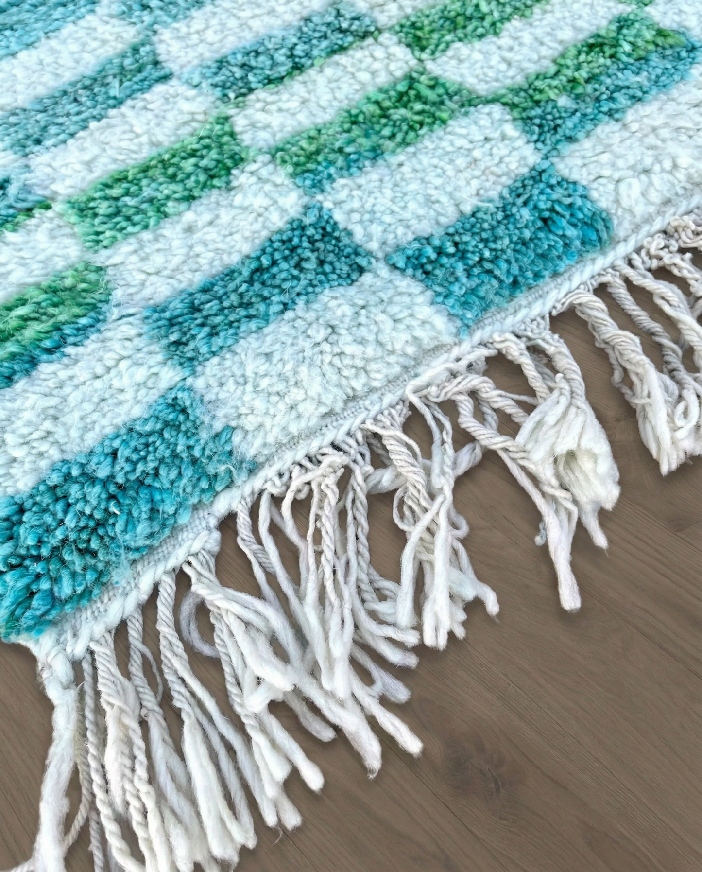 IBTISSAM Beni Ourain teal checker grid Moroccan rug close-up of hand-tied fringe and kilim band detail, by NURA