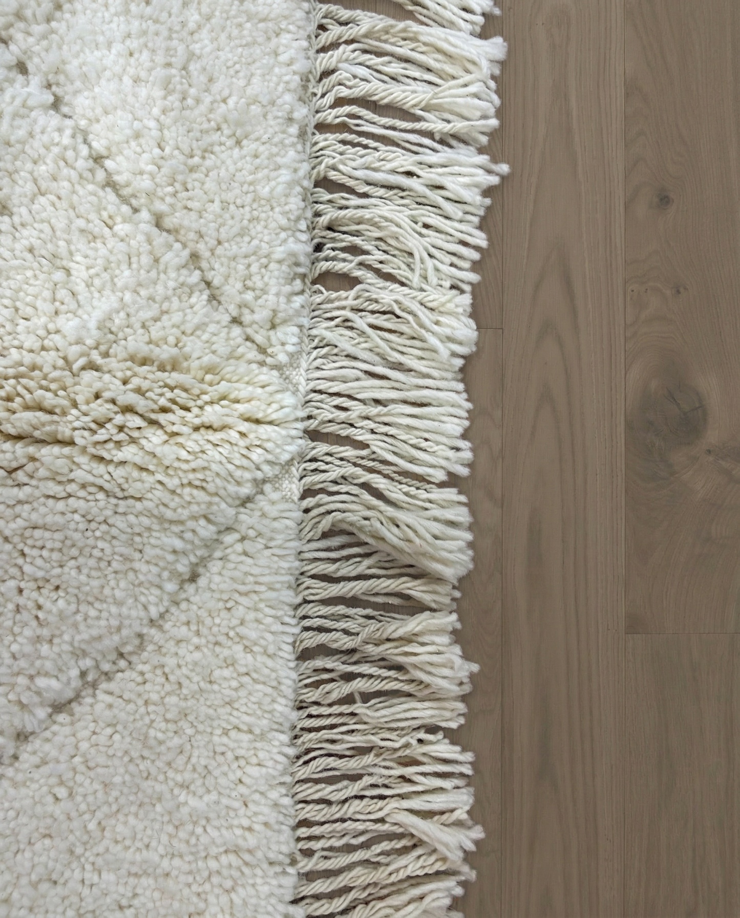IMANE Beni Ourain cream textured diamond lattice Moroccan rug close-up of hand-tied fringe and kilim band detail, by NURA