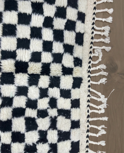 JAMILA Beni Ourain black checker grid Moroccan rug close-up of hand-tied fringe and kilim band detail, by NURA