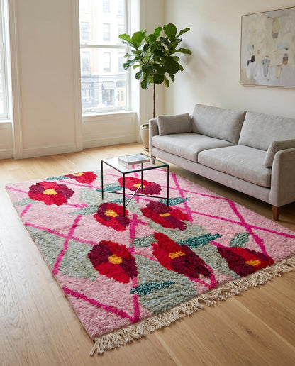 A plush pink Moroccan floral rug by NURA anchors a bright living room, adding a bold pop of color and cozy texture.