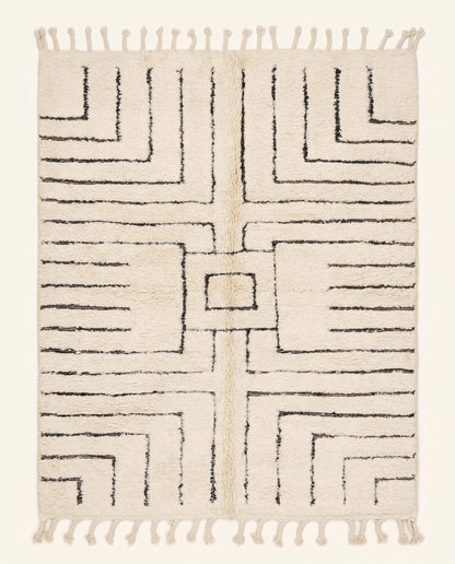 A plush Beni Ourain Moroccan rug by NURA featuring a bold black geometric maze motif on a soft cream hand-knotted wool pile.