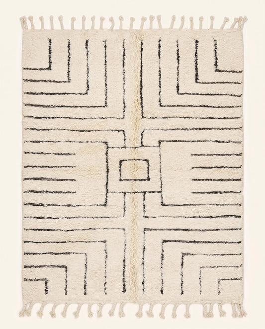 A plush Beni Ourain Moroccan rug by NURA featuring a bold black geometric maze motif on a soft cream hand-knotted wool pile.