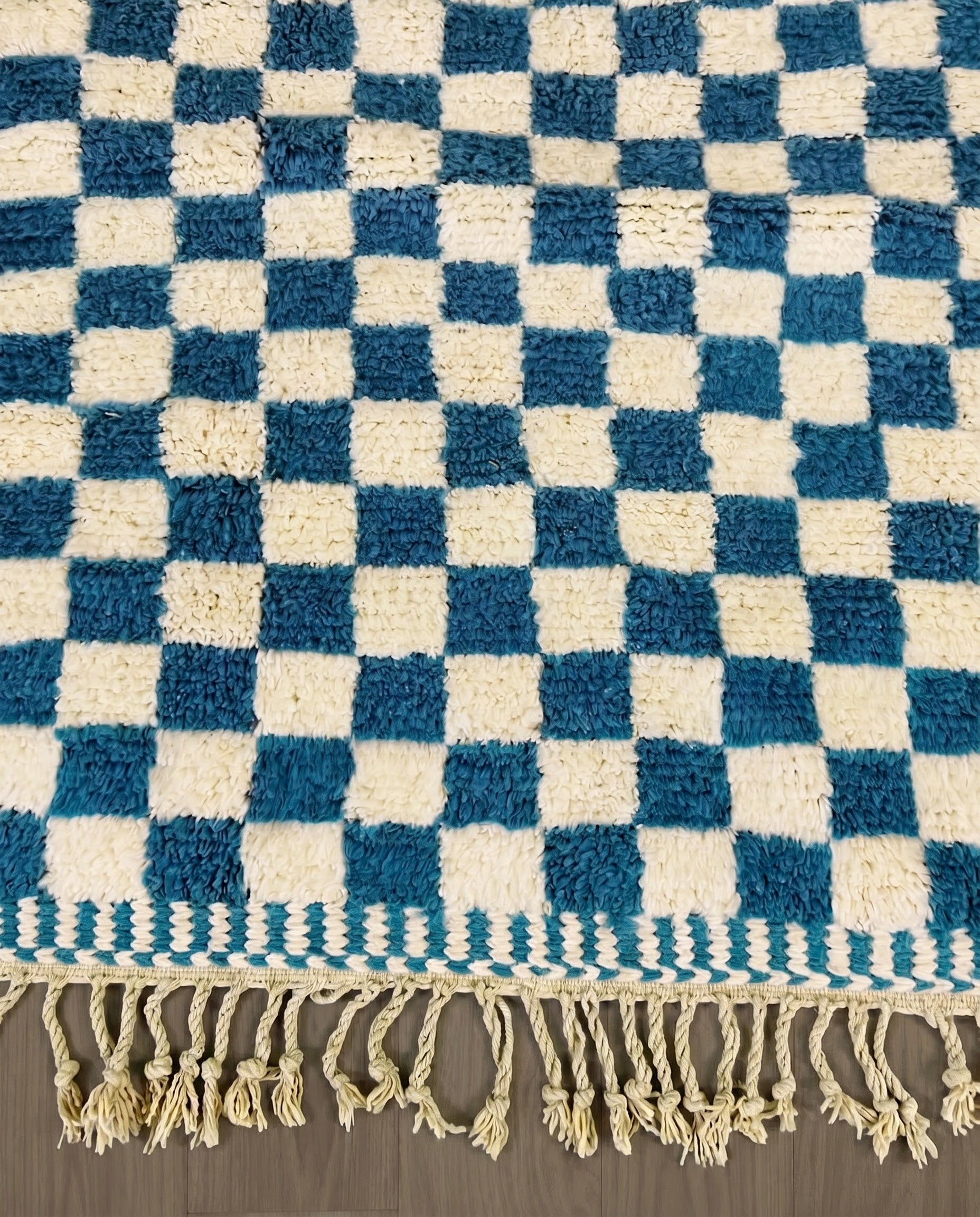MAJDA Beni Ourain blue checker grid Moroccan rug close-up of hand-tied fringe and kilim band detail, by NURA