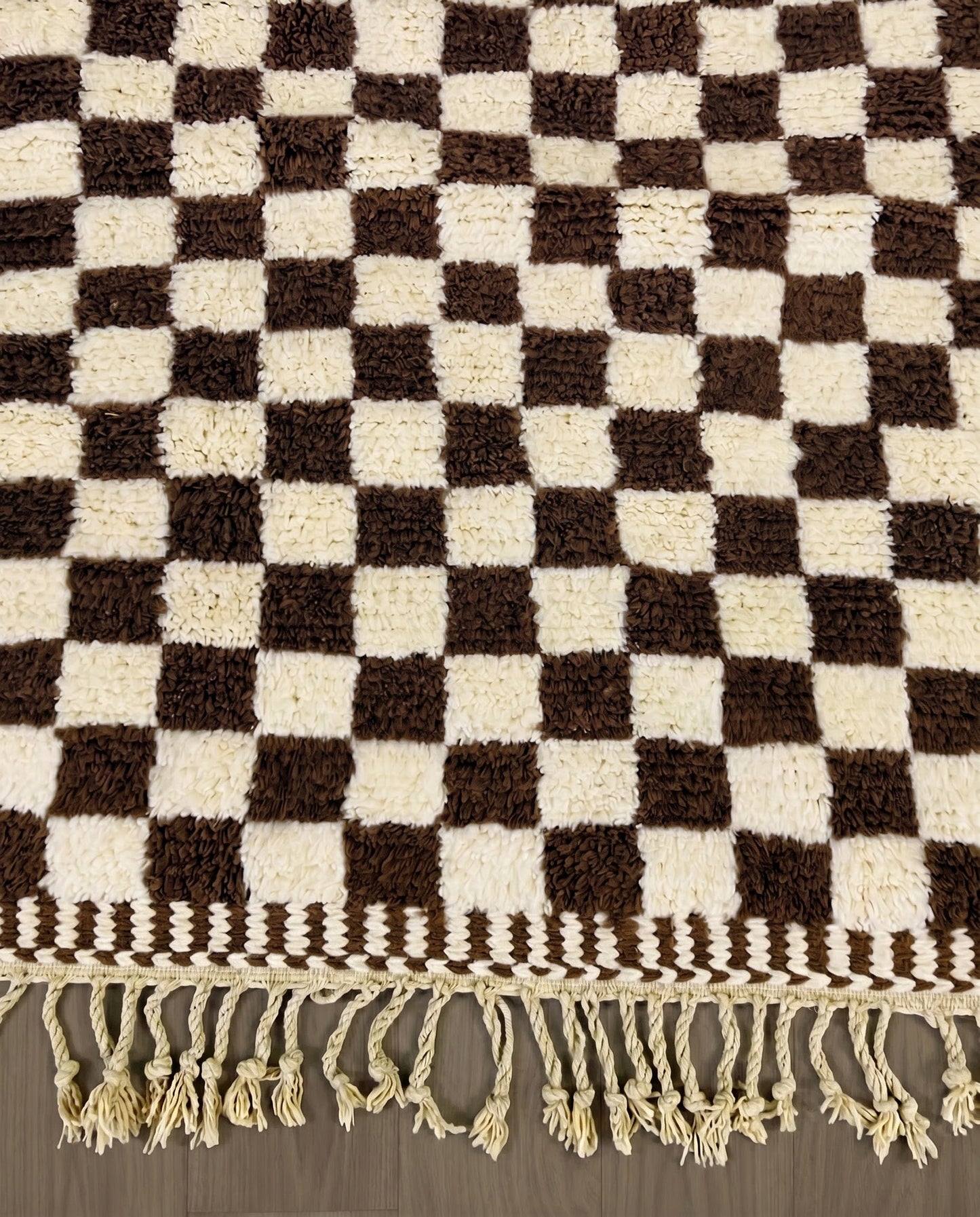 MAJIDA Beni Ourain chocolate checker grid Moroccan rug close-up of hand-tied fringe and kilim band detail, by NURA