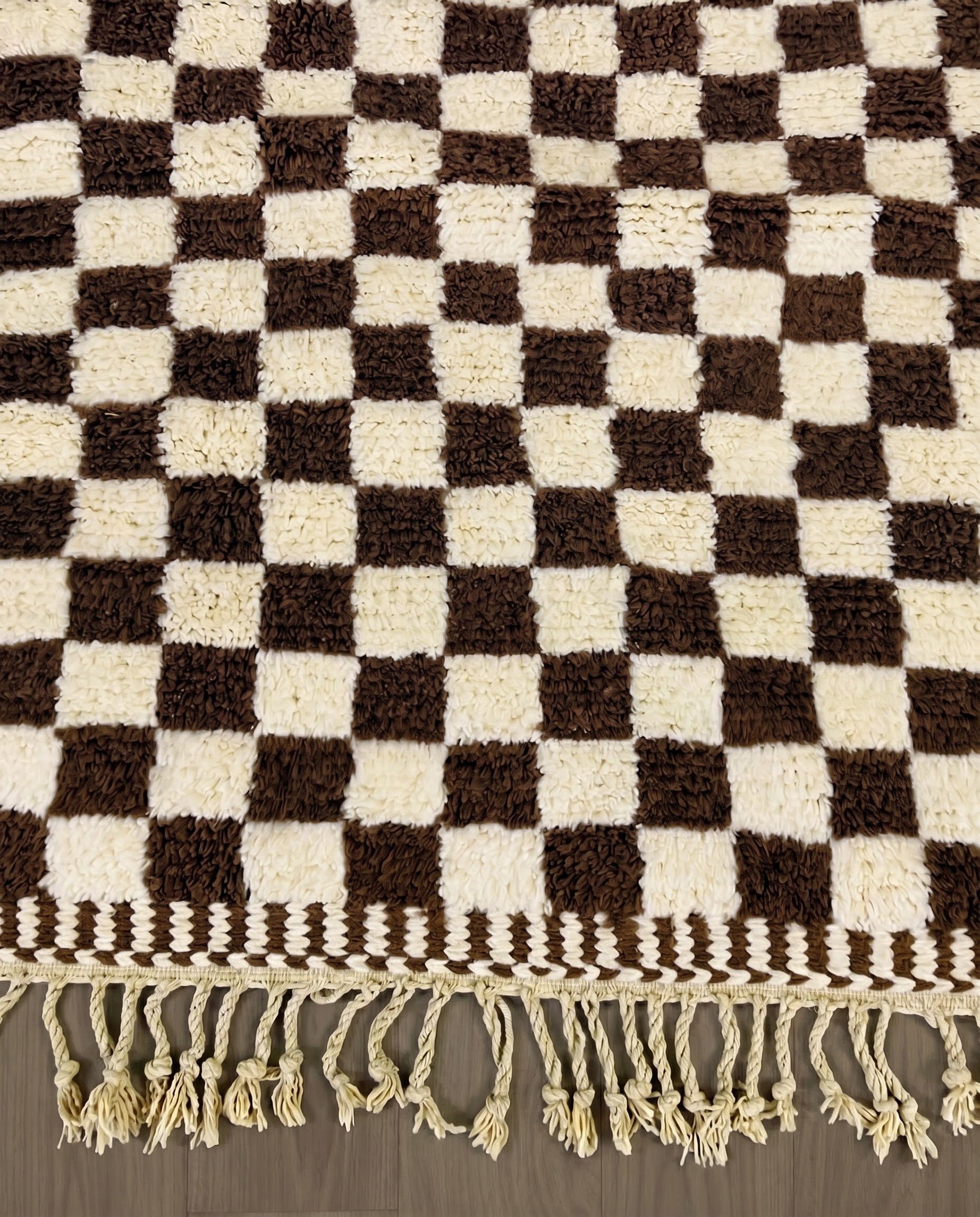 MAJIDA Beni Ourain chocolate checker grid Moroccan rug close-up of hand-tied fringe and kilim band detail, by NURA