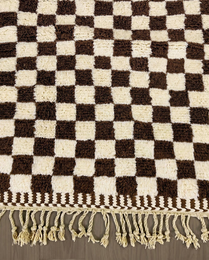 MAJIDA Beni Ourain chocolate checker grid Moroccan rug close-up of hand-tied fringe and kilim band detail, by NURA