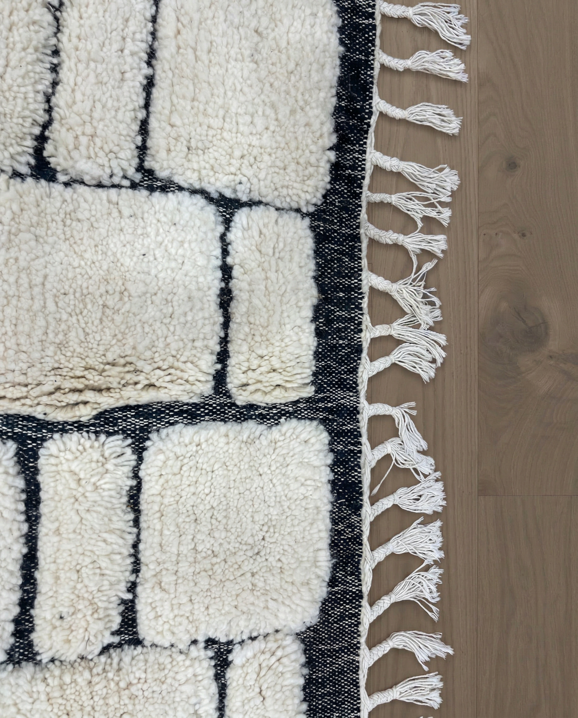 MERIEM Beni Ourain ivory abstract block grid Moroccan rug close-up of hand-tied fringe and kilim band detail, by NURA