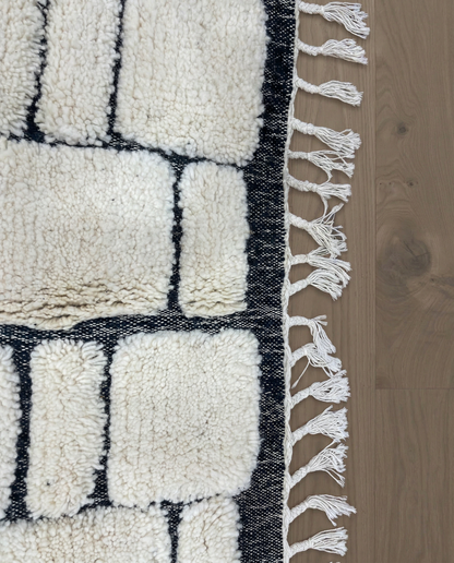 MERIEM Beni Ourain ivory abstract block grid Moroccan rug close-up of hand-tied fringe and kilim band detail, by NURA